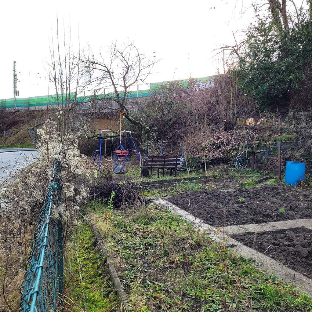 Winterlicher Blick in einen der Kleingärten beim Kitzinger Bahnhof: Schaukel, Hängesessel, Sitzbank, Bäume, Beete