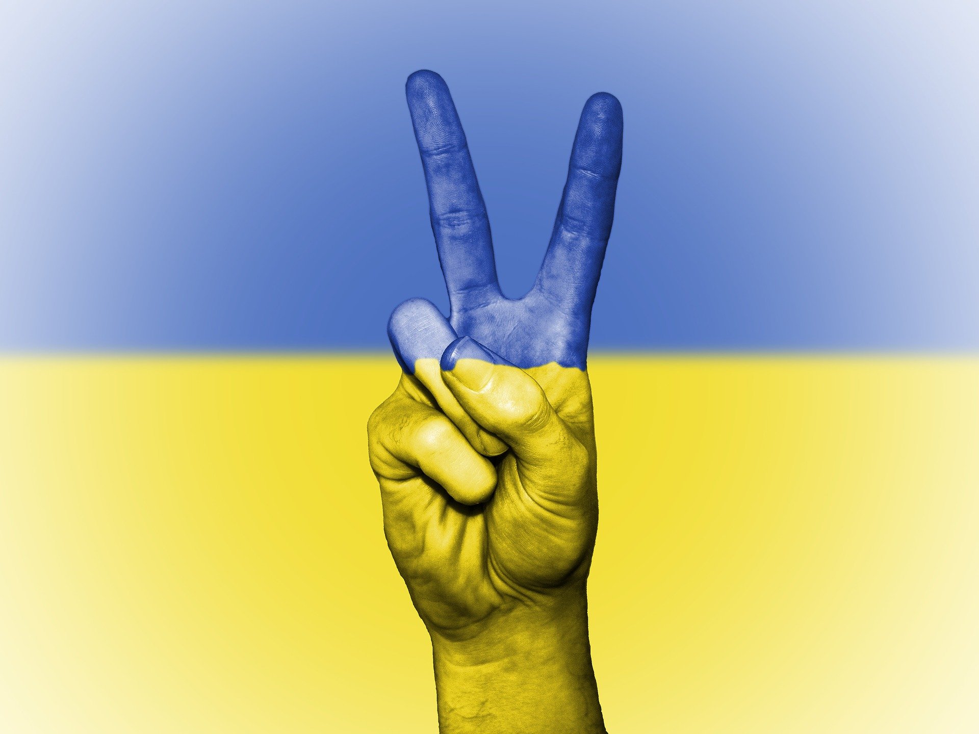 Hand zeigt das Peacezeichen, Hand ist in den Fraben der Ukraine-Flagge bemalt (gelb-blau)
