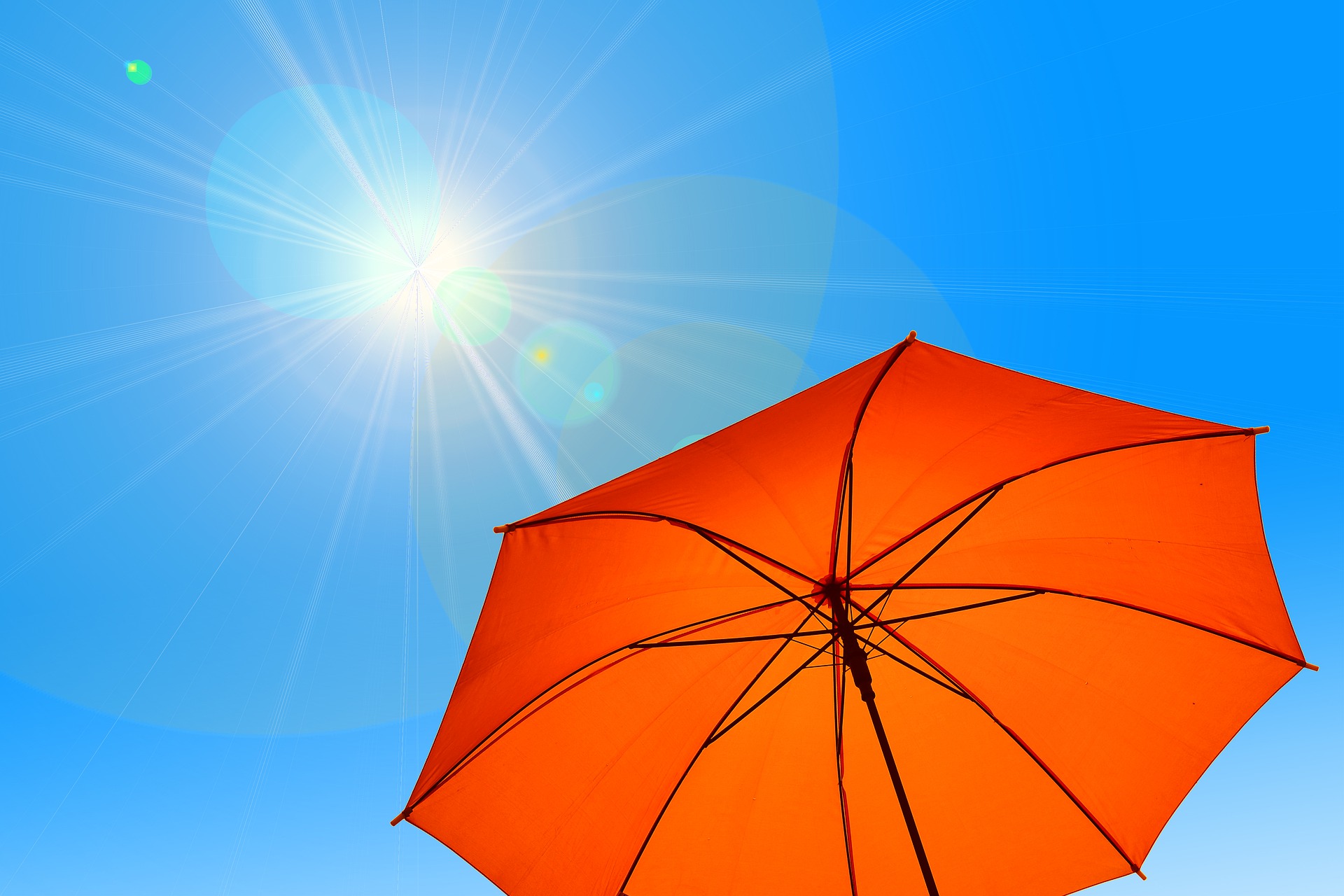 roter regenschirm wird als Sonnenschutz in die Sonne gehalten