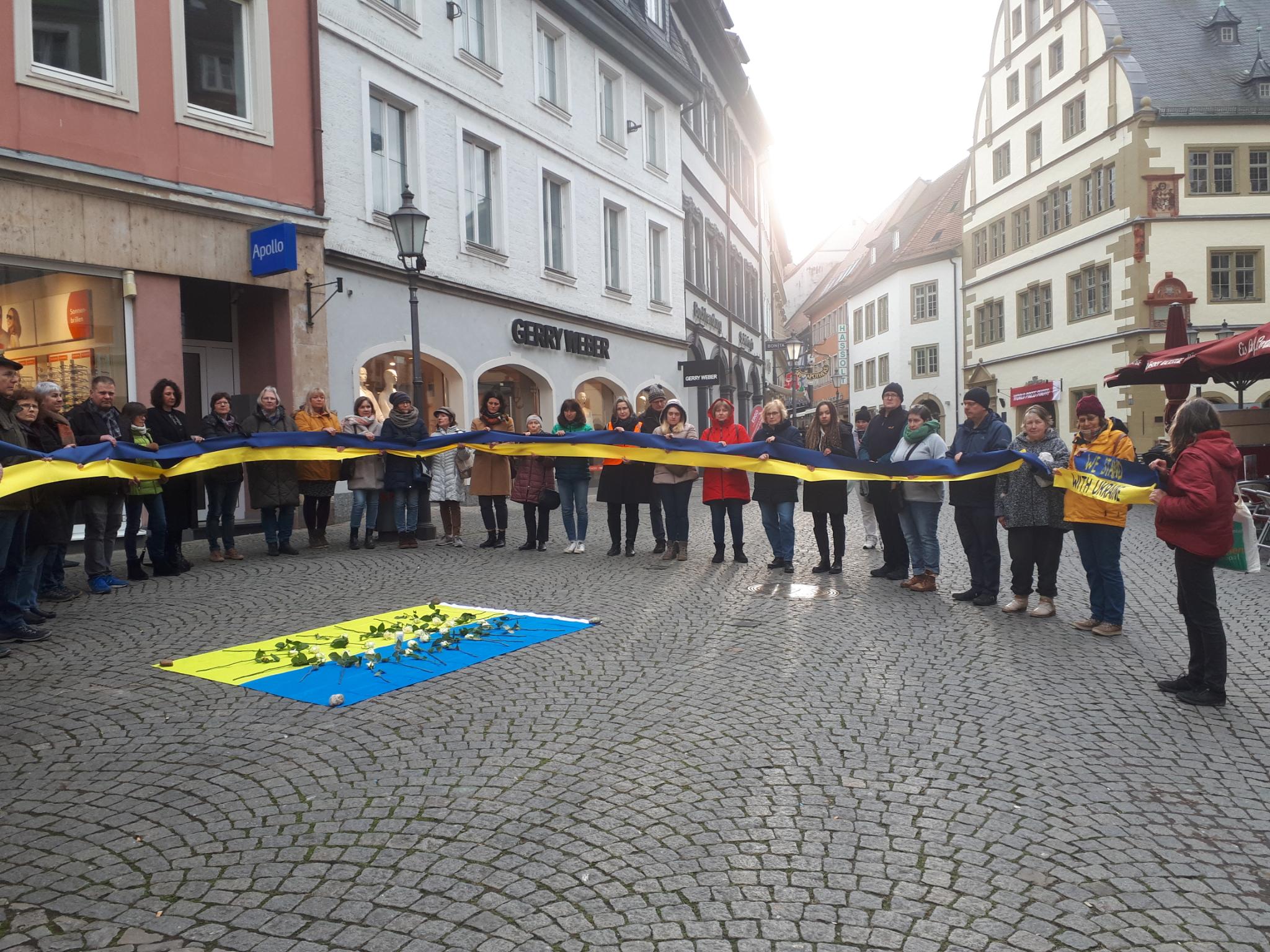 Mahnwache auf dem Kitzinger Marktplatz. Menschenkette um die Ukraine-Flagge. Foto: Christa Büttner